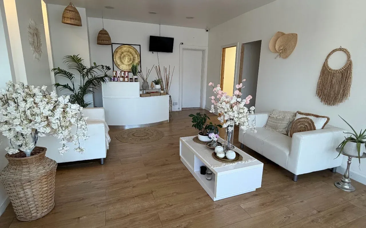 The Wow Beauty reception with white sofas, rattan lights, plants and blossom